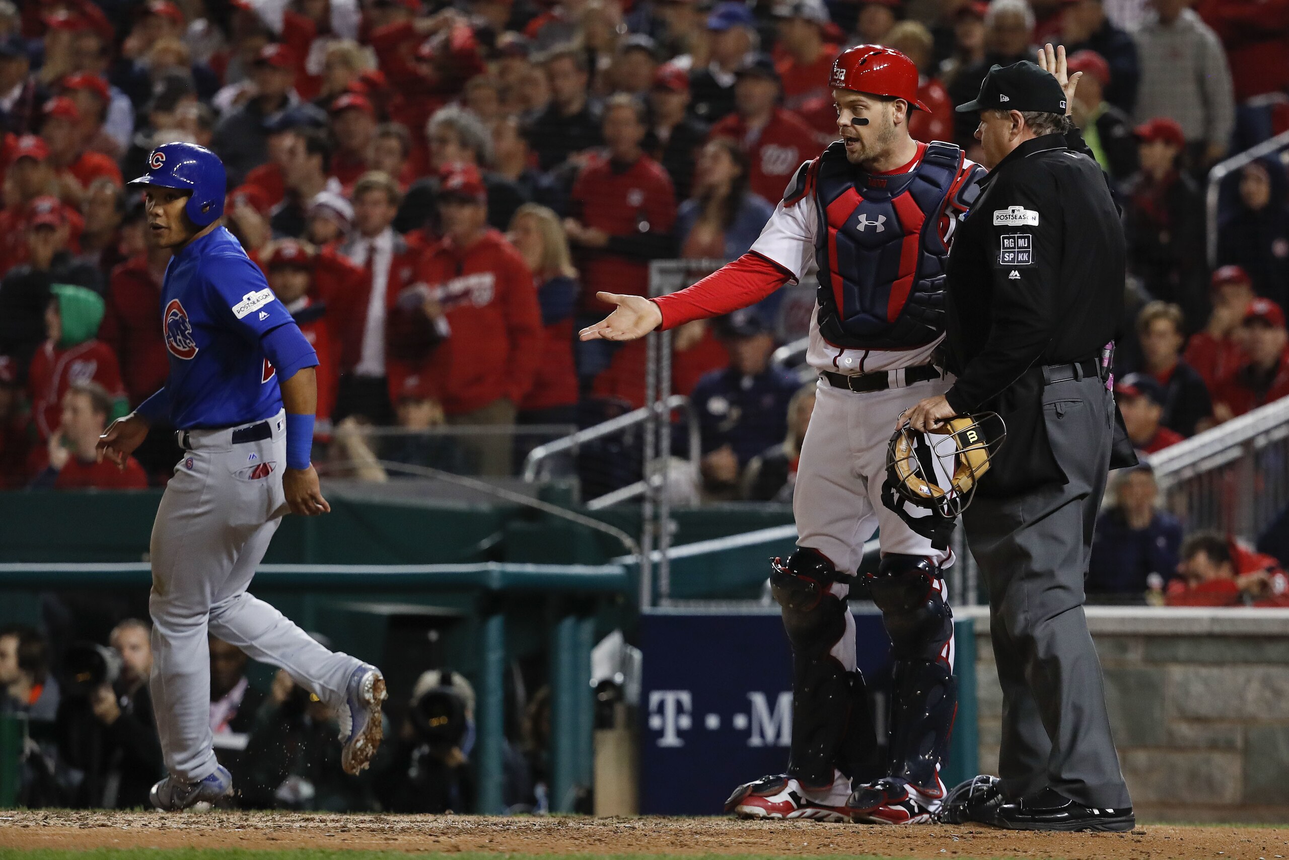 Washington Nationals catcher Matt Wieters (32) talks with umpire Jerry Lane as Chicago Cubs' Addison Russell, left, scores on a passed ball and throwing error by Wieters that allowed batter Javier Baez to reach second after striking out, during the firth inning in Game 5 of baseball's National League Division Series, at Nationals Park, Thursday, Oct. 12, 2017 in Washington. (AP Photo/Pablo Martinez Monsivais)