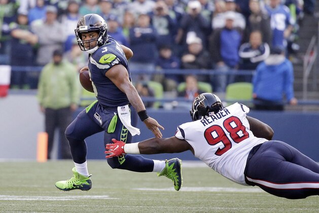 Seattle Seahawks quarterback Russell Wilson, left, scrambles away from Houston Texans' D.J. Reader in the second half of an NFL football game, Sunday, Oct. 29, 2017, in Seattle. The Seahawks won 41-38. (AP Photo/Elaine Thompson)