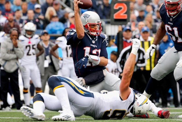 FOXBORO, MA - OCTOBER 29:  Tom Brady #12 of the New England Patriots throws as he is tackled by Joey Bosa #99 of the Los Angeles Chargers during the second quarter of a game at Gillette Stadium on October 29, 2017 in Foxboro, Massachusetts.  (Photo by Jim Rogash/Getty Images)