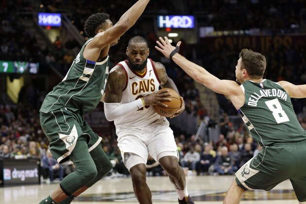 Cleveland Cavaliers' LeBron James, center, drives between Milwaukee Bucks' Giannis Antetokounmpo, left, from Greece, and Matthew Dellavedova, from Australia, in the first half of an NBA basketball game, Tuesday, Nov. 7, 2017, in Cleveland. (AP Photo/Tony Dejak)