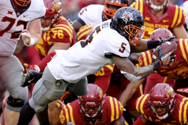 AMES, IA - NOVEMBER 11: Running back Justice Hill #5 of the Oklahoma State Cowboys dives over Iowa State Cyclones defenders to score a touchdown in the first half of play at Jack Trice Stadium on November 11, 2017 in Ames, Iowa. (Photo by David Purdy/Getty Images)