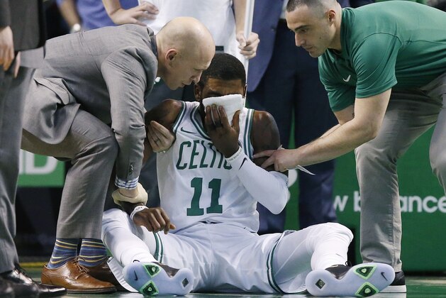 Team personnel assist Boston Celtics' Kyrie Irving (11) after he was injured during the first quarter of an NBA basketball game against the Charlotte Hornets in Boston, Friday, Nov. 10, 2017. Irving took an elbow to the face and left the game. (AP Photo/Michael Dwyer)