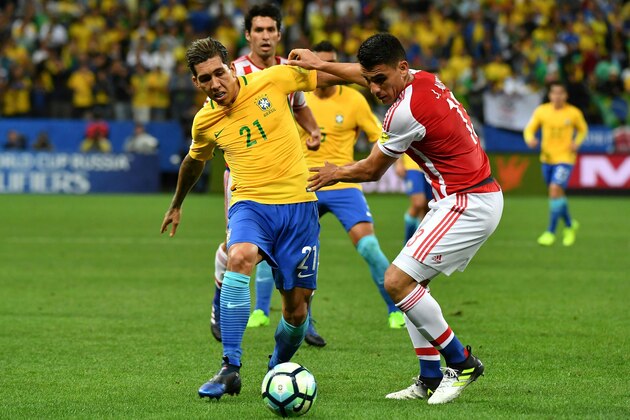 Brazil's forward Roberto Firmino (L) vies for the ball with Paraguay's defender Junior Alonso during their 2018 FIFA World Cup qualifier football match in Sao Paulo, Brazil on March 28, 2017. / AFP PHOTO / NELSON ALMEIDA        (Photo credit should read NELSON ALMEIDA/AFP/Getty Images)