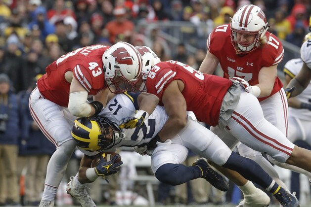 Michigan's Chris Evans is stopped by Wisconsin's Ryan Connelly (43), T.J. Edwards and Andrew Van Ginkel during the second half of an NCAA college football game Saturday, Nov. 18, 2017, in Madison, Wis. (AP Photo/Morry Gash)