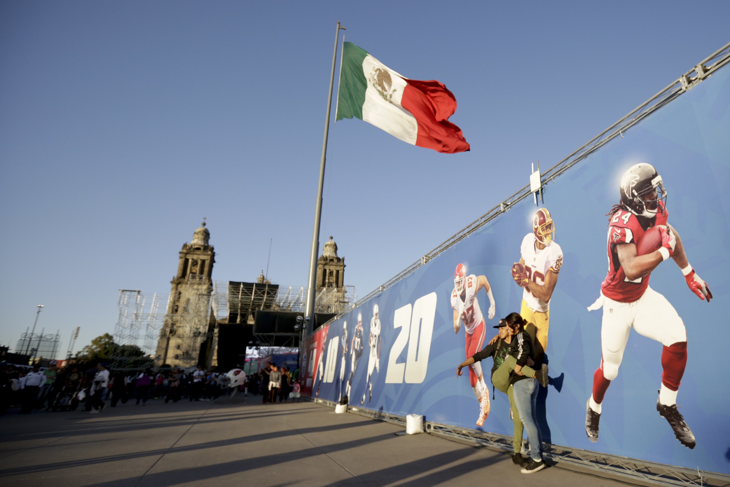 Fans interact during NFL football's Fan Fest at Zocalo Square Saturday, Nov. 18, 2017, in Mexico City. Thousands of football fans descended on the city's historic main plaza Saturday, one day before the New England Patriots face the Oakland Raiders in a football game at Aztec Stadium. (AP Photo/Gregory Bull)