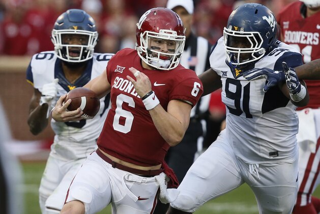 Oklahoma quarterback Baker Mayfield (6) carries past West Virginia safety Dravon Askew-Henry (6) and defensive lineman Ezekiel Rose (91) in the second quarter of an NCAA college football game in Norman, Okla., Saturday, Nov. 25, 2017. (AP Photo/Sue Ogrocki)