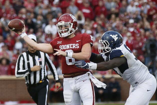 Oklahoma quarterback Baker Mayfield (6) throws under pressure from a West Virginia defender during an NCAA college football game in Norman, Okla., Saturday, Nov. 25, 2017. (AP Photo/Sue Ogrocki)