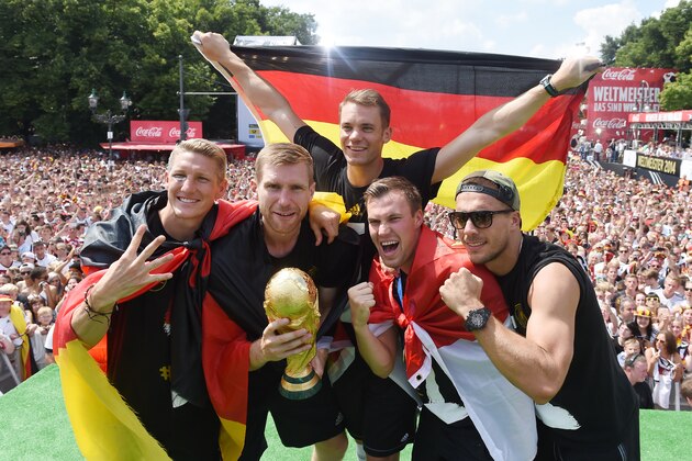 German soccer players from left: Bastian Schweinsteiger, Per Mertesacker, goalie Manuel Neuer, Kevin Grosskreutz, and Lukas Podolski celebrate on stage at the German team victory ceremony , near the Brandenburg Gate in Berlin,  Tuesday July 15,  2014.  Germany's World Cup winners shared their fourth title with hundreds of thousands of fans by parading the trophy through cheering throngs to celebrate at the Brandenburg Gate on Tuesday. An estimated 400,000 people packed the