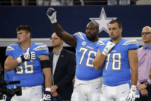 Los Angeles Chargers' Russell Okung (76) raises his fist as he stands between Dan Feeney (66) and Michael Schofield (78) during the playing of the national anthem before the first half of an NFL football game against the Dallas Cowboys on Thursday, Nov. 23, 2017, in Arlington, Texas. (AP Photo/Ron Jenkins)