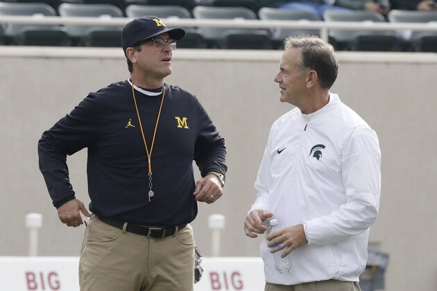 FILE - In this Oct. 29, 2016, file photo, Michigan head coach Jim Harbaugh, left, greets Michigan State head coach Mark Dantonio at midfield before their NCAA college football game in East Lansing, Mich. Michigan State plays at No. 7 Michigan on Saturday, Oct. 7, 2017. (AP Photo/Carlos Osorio, File)
