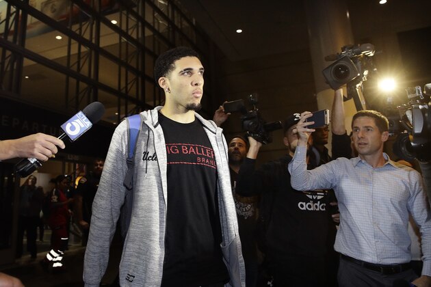 UCLA basketball player LiAngelo Ball is surrounded by reporters and photographers as he leaves Los Angeles International Airport on Tuesday, Nov. 14, 2017, in Los Angeles. Three UCLA basketball players–Ball, Jalen Hill and Cody Riley–detained in China on suspicion of shoplifting returned home, where they may be disciplined by the school as a result of the international scandal. (AP Photo/Jae C. Hong)