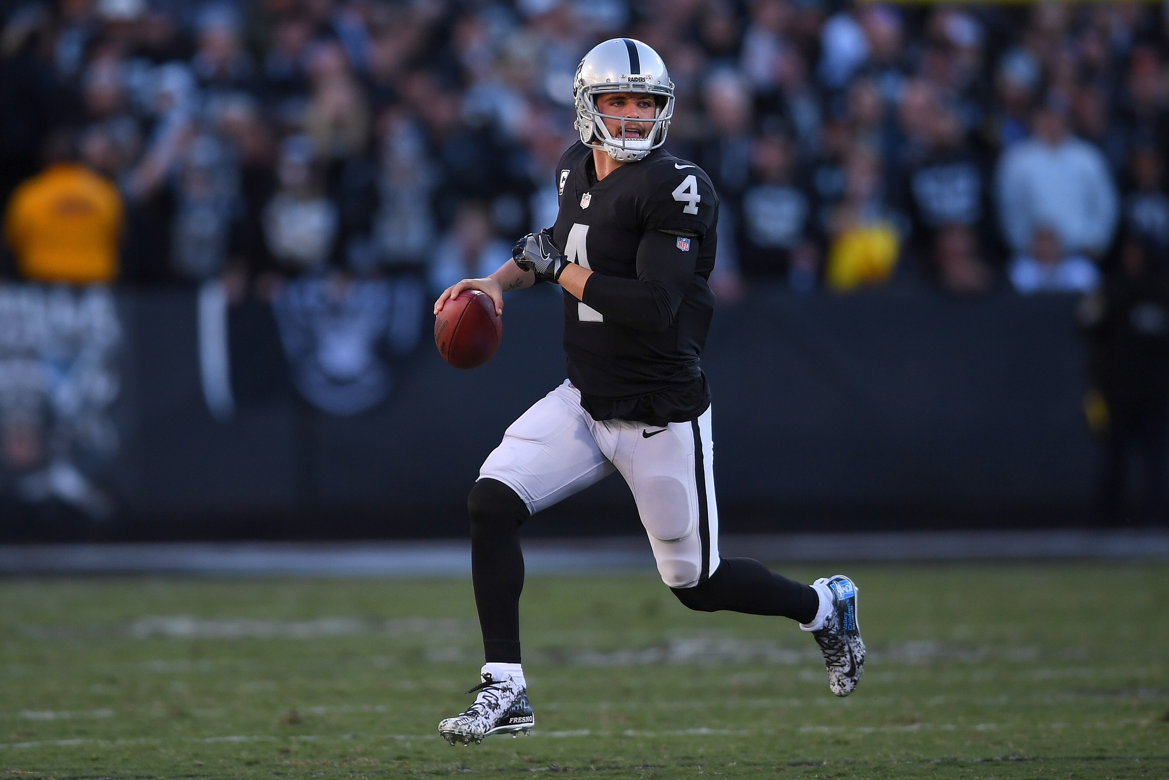 OAKLAND, CA - DECEMBER 03:  Derek Carr #4 of the Oakland Raiders looks to throw a pass while scrambling with the ball against the New York Giants during their NFL football game at Oakland-Alameda County Coliseum on December 3, 2017 in Oakland, California.  (Photo by Thearon W. Henderson/Getty Images)