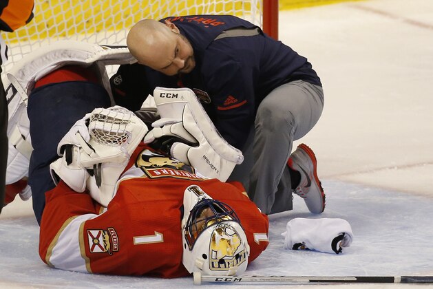 Florida Panthers head athletic trainer Dave DiNapoli attends to goalie Roberto Luongo (1) after a play during the second period of an NHL hockey game against the New York Islanders, Monday, Dec. 4, 2017, in Sunrise, Fla. Luongo had to be helped off the ice and wasn't able to put any weight on the leg. He was replaced by James Reimer. (AP Photo/Wilfredo Lee)