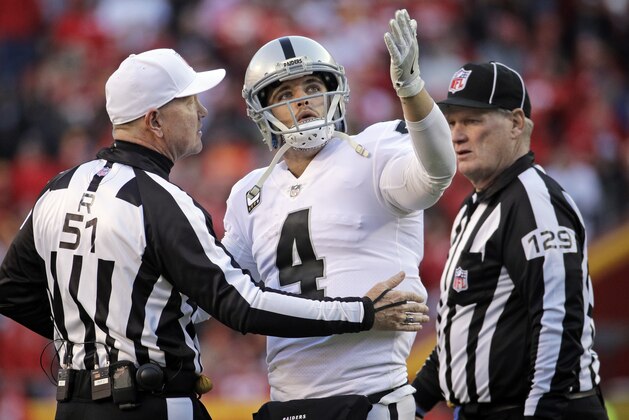 Oakland Raiders quarterback Derek Carr (4) has works with referee Carl Cheffers (51) and umpire Bill Schuster (129) during the second half of an NFL football game against the Kansas City Chiefs in Kansas City, Mo., Sunday, Dec. 10, 2017. The Kansas City Chiefs won 26-15. (AP Photo/Charlie Riedel)