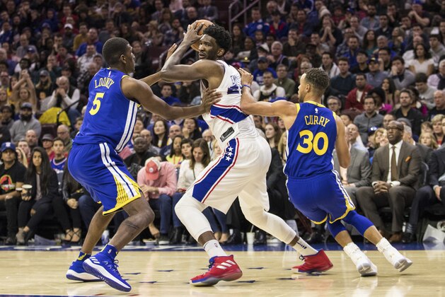 Philadelphia 76ers' Joel Embiid, of Cameroon, center, tries to make his move with Golden State Warriors' Kevon Looney, left, and Stephen Curry, right, defending during the second half of an NBA basketball game, Saturday, Nov. 18, 2017, in Philadelphia. The Warriors won 124-116. (AP Photo/Chris Szagola)
