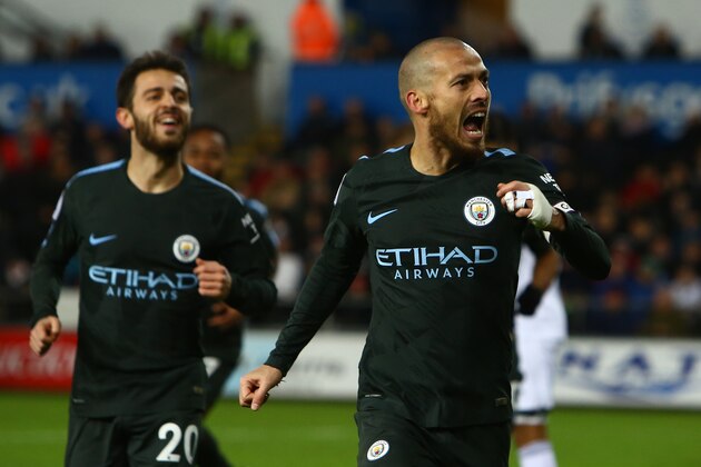 Manchester City's Spanish midfielder David Silva (R) celebrates after scoring their third goal during the English Premier League football match between Swansea City and Manchester City at The Liberty Stadium in Swansea, south Wales on December 13, 2017. / AFP PHOTO / Geoff CADDICK / RESTRICTED TO EDITORIAL USE. No use with unauthorized audio, video, data, fixture lists, club/league logos or 'live' services. Online in-match use limited to 75 images, no video emulation. No use in betting, games or single club/league/player publications.  /         (Photo credit should read GEOFF CADDICK/AFP/Getty Images)