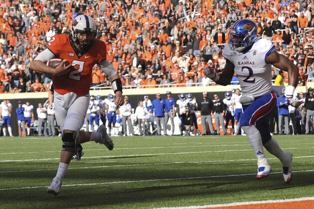Kansas defensive end Dorance Armstrong Jr., right, chases after Oklahoma State quarterback Mason Rudolph as he scores a touchdown in the first half of an NCAA college football game between Kansas and Oklahoma St in Stillwater, Okla., Saturday, Nov. 25, 2017. (AP Photo/Brody Schmidt) Kansas defensive end Dorance Armstrong Jr., right, chases after Oklahoma State quarterback Mason Rudolph as he scores a touchdown in the first half of an NCAA college football game between Kansas and Oklahoma St in Stillwater, Okla., Saturday, Nov. 25, 2017. (AP Photo/Brody Schmidt)