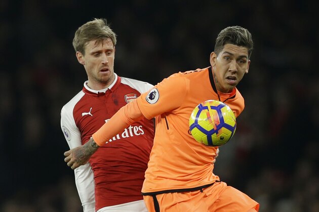 Arsenal's Nacho Monreal, left, vies for the ball with Liverpool's Roberto Firmino during their English Premier League soccer match between Arsenal and Liverpool at the Emirates stadium London, Friday, Dec. 22, 2017. (AP Photo/Alastair Grant)