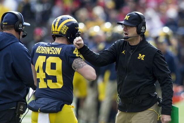 Michigan head coach Jim Harbaugh, right, congratulates long snapper Andrew Robinson (49) after a Michigan touchdown in the first quarter of an NCAA college football game against Ohio State in Ann Arbor, Mich., Saturday, Nov. 25, 2017. (AP Photo/Tony Ding)