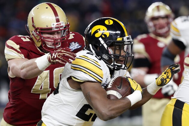 Boston College linebacker Kevin Bletzer (49) prepares to tackle Iowa running back Akrum Wadley (25) who runs with the ball during the first quarter of the Pinstripe Bowl NCAA college football game, Wednesday, Dec. 27, 2017, in New York. (AP Photo/Kathy Willens)