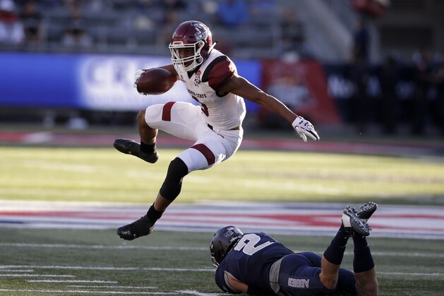 New Mexico State running back Larry Rose III (3) leaps over Utah State safety Dallin Leavitt in the first half of the Arizona Bowl NCAA college football game Friday, Dec. 29, 2017, in Tucson, Ariz. (AP Photo/Rick Scuteri)