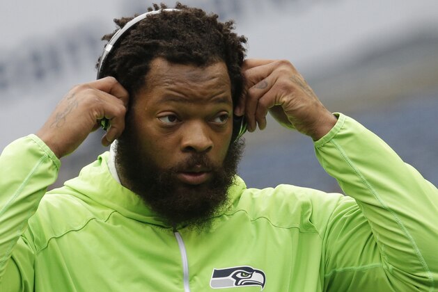 Seattle Seahawks defensive end Michael Bennett wears headphones as he stands on the field during warmups before an NFL football game against the Houston Texans, Sunday, Oct. 29, 2017, in Seattle. (AP Photo/Elaine Thompson)