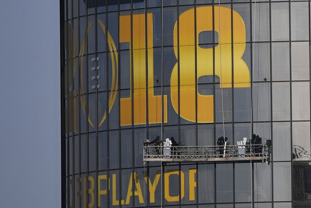 Workers place signage on a hotel announcing the NCAA national championship football game, Wednesday, Jan. 3, 2018, in Atlanta. Alabama and Georgia won their College Football Playoff semifinals on Monday and will meet in the national championship next week in Atlanta. (AP Photo/Mike Stewart)