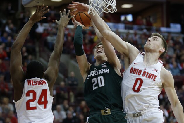 Michigan State guard Matt McQuaid, center, goes up to shoot between Ohio State forward Andre Wesson, left, and center Micah Potter during the first half of an NCAA college basketball game in Columbus, Ohio, Sunday, Jan. 7, 2018. (AP Photo/Paul Vernon)
