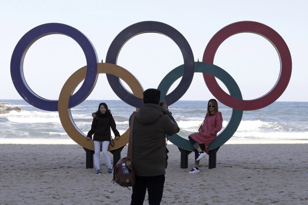 This Oct. 30, 2017, photo show visitors posing with the Olympic Rings at the Gyeongpodae beach, in Gangneung, South Korea. South Korea's sleepy skiing destination of Pyeongchang is finally looking like a Winter Olympics host city after more than a decade of work, two failed bids, and chapters of controversy over venue locations, construction delays and costs. (AP Photo/Ahn Young-joon)