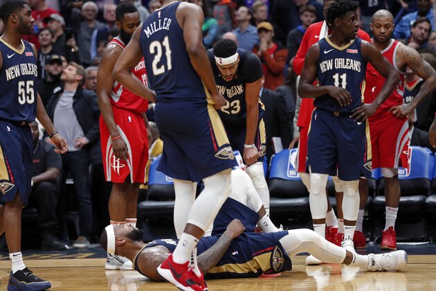 New Orleans Pelicans center DeMarcus Cousins lies on the court after injuring his left achilles tendon, while surrounded by teammates, guard E'Twaun Moore (55), forward Darius Miller (21), forward Anthony Davis (23) and guard Jrue Holiday (11), in the second half of an NBA basketball game against the Houston Rockets in New Orleans, Friday, Jan. 26, 2018. The Pelicans won 115-113. (AP Photo/Gerald Herbert)