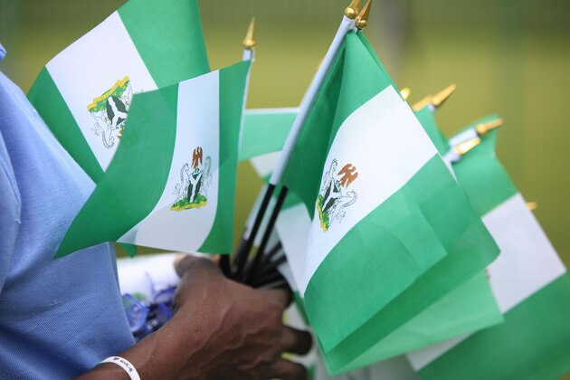 An unidentified woman sells Nigerian national flags, during an event to mark Nigeria independence day, in Lagos, Nigeria. Tuesday, Oct. 1, 2013 . Nigeria marked 53 years of independence Tuesday with little to celebrate,  scores of families are in mourning over killings by suspected Islamic extremists, security forces on high alert against feared bomb attacks and the government rift by an internal power struggle. (AP Photo/Sunday Alamba)