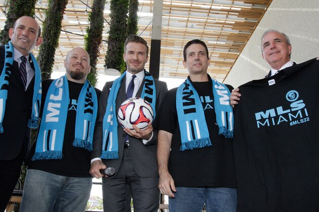 Former  England and Manchester United star, David Beckham(C) poses for photos after holding a press conference at the Perez Art Museum Miami, in Miami, Florida on February 5, 2014. Beckham said Wednesday that he will buy a US team to play Major League Soccer and bring it to Miami, confirming the worst-kept secret in world football. At left is Major League Soccer Commissioner, Don Garber(L) and Miami-Dade County Mayor, Carlos A. Gimenez is at right. AFP PHOTO / Alexia FODERE        (Photo credit should read Alexia Fodere/AFP/Getty Images)