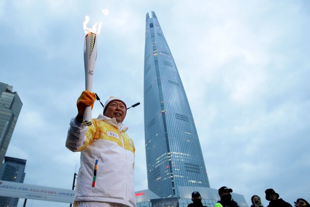 SEOUL, SOUTH KOREA - JANUARY 14:  Shin Dong-bin, chairman of Lotte Group, holds the PyeongChang 2018 Winter Olympics torch in front of the Lotte World Tower during the PyeongChang 2018 Winter Olympic Games torch relay on January 14, 2018 in Seoul, South Korea.  (Photo by Chung Sung-Jun/Getty Images)