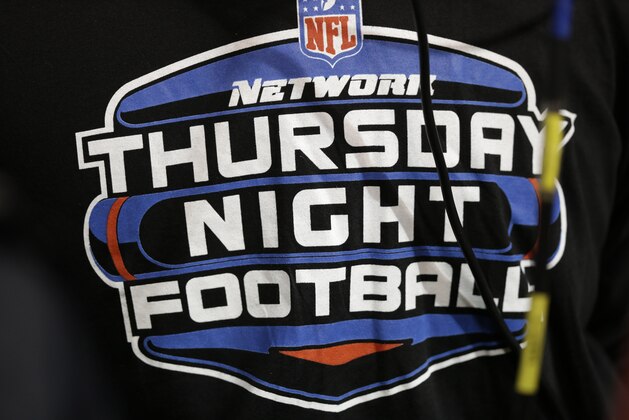 A Thursday Night Football logo is seen on the back of a cameraman before an NFL football game between the Minnesota Vikings and the Tampa Bay Buccaneers Thursday, Oct. 25, 2012, in Minneapolis. (AP Photo/Charlie Neibergall)