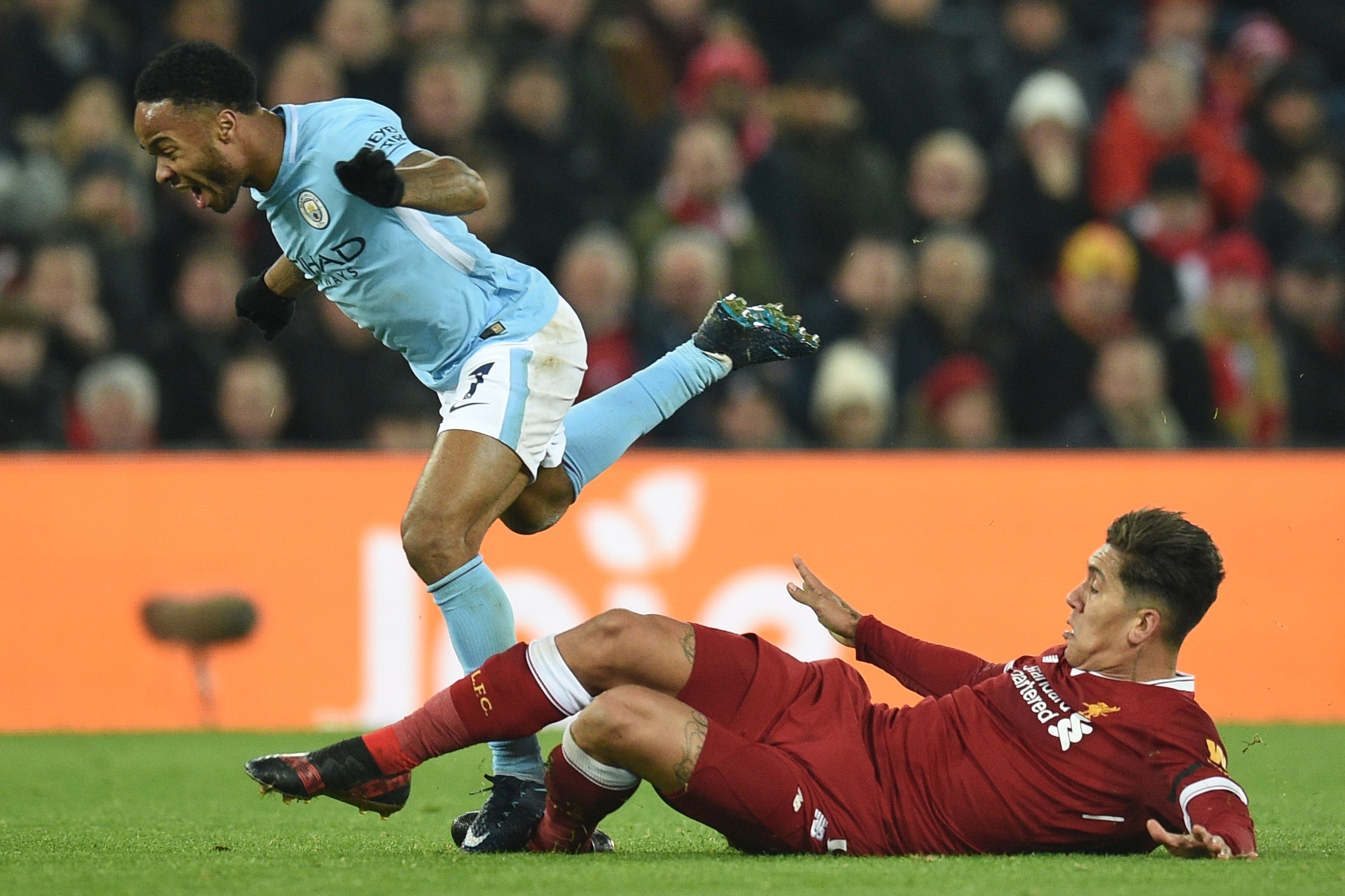Manchester City's English midfielder Raheem Sterling (L) goes down as Liverpool's Brazilian midfielder Roberto Firmino (R) attempts a tackle during the English Premier League football match between Liverpool and Manchester City at Anfield in Liverpool, north west England on January 14, 2018. / AFP PHOTO / Oli SCARFF / RESTRICTED TO EDITORIAL USE. No use with unauthorized audio, video, data, fixture lists, club/league logos or 'live' services. Online in-match use limited to 75 images, no video emulation. No use in betting, games or single club/league/player publications. / (Photo credit should read OLI SCARFF/AFP/Getty Images) Manchester City's English midfielder Raheem Sterling (L) goes down as Liverpool's Brazilian midfielder Roberto Firmino (R) attempts a tackle during the English Premier League football match between Liverpool and Manchester City at Anfield in Liverpool, north west England on January 14, 2018. / AFP PHOTO / Oli SCARFF / RESTRICTED TO EDITORIAL USE. No use with unauthorized audio, video, data, fixture lists, club/league logos or 'live' services. Online in-match use limited to 75 images, no video emulation. No use in betting, games or single club/league/player publications. / (Photo credit should read OLI SCARFF/AFP/Getty Images)