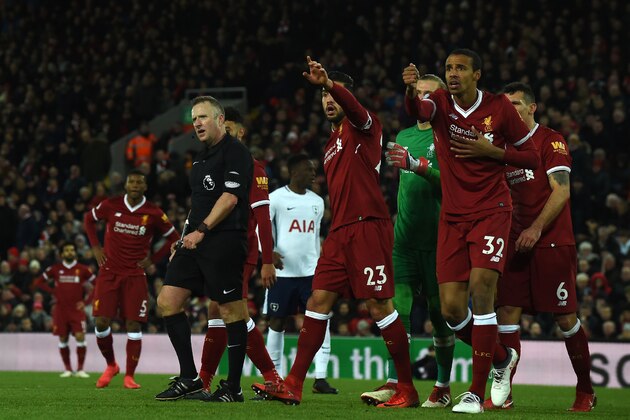 Referee Johnathan Moss (C) awards the first penalty as Liverpool players discuss during the English Premier League football match between Liverpool and Tottenham Hotspur at Anfield in Liverpool, north west England on February 4, 2018. / AFP PHOTO / PAUL ELLIS / RESTRICTED TO EDITORIAL USE. No use with unauthorized audio, video, data, fixture lists, club/league logos or 'live' services. Online in-match use limited to 75 images, no video emulation. No use in betting, games or single club/league/player publications.  /         (Photo credit should read PAUL ELLIS/AFP/Getty Images)