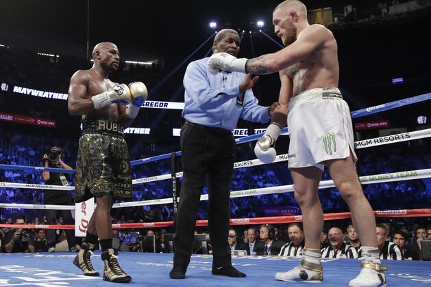 Referee Robert Byrd, center, gets between Floyd Mayweather Jr., left, and Conor McGregor in a super welterweight boxing match Saturday, Aug. 26, 2017, in Las Vegas. (AP Photo/Eric Jamison)
