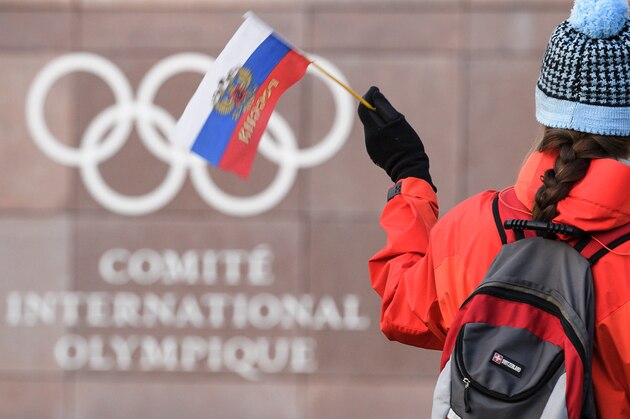 A supporter waves a Russian flag in front of the logo of the International Olympic Committee (IOC) at their headquarters on December 5, 2017 in Pully near Lausanne.
The International Olympic Committee meets to decide whether to bar Russia from the 2018 Winter Olympics for doping violations, in one of the weightiest decisions ever faced by the Olympic movement. / AFP PHOTO / Fabrice COFFRINI        (Photo credit should read FABRICE COFFRINI/AFP/Getty Images)