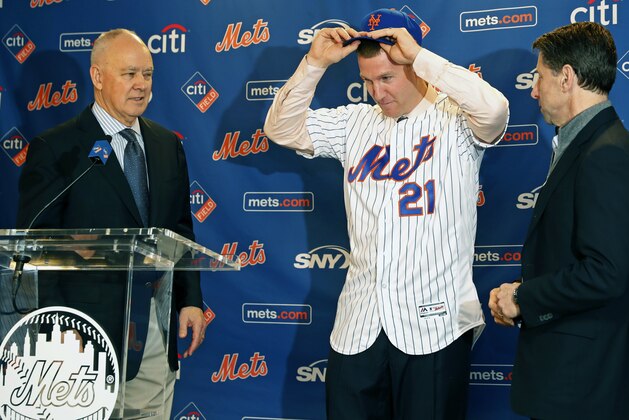 New York Mets general manager Sandy Alderson, left, and Mets owner Jeff Wilpon, right, watch as newly-signed Mets' third baseman Todd Frazier dons a Mets cap and jersey during a press conference, Wednesday, Feb. 7, 2018, at CitiField in New York. Frazier reportedly signed a two-year deal, finalized on Wednesday. The contract calls for Frazier to be paid $8 million this year and $9 million in 2019. (AP Photo/Kathy Willens)