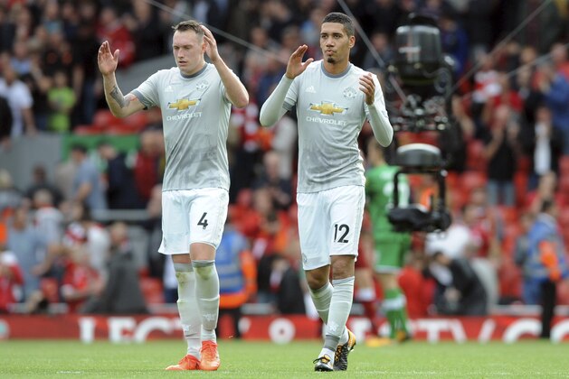 Manchester United's Phil Jones, left, and Manchester United's Chris Smalling applause he audience after during the English Premier League soccer match between Liverpool and Manchester United at Anfield, Liverpool, England, Saturday, Oct. 14, 2017. (AP Photo/Rui Vieira)