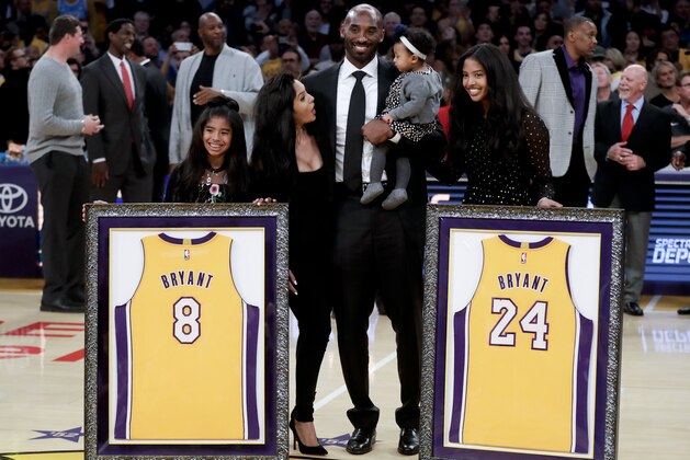Former Los Angeles Laker Kobe Bryant poses with his family during an NBA basketball game between the Los Angeles Lakers and the Golden State Warriors in Los Angeles, Monday, Dec. 18, 2017. The Lakers retired Bryant's No. 8 and No. 24 jersey during a halftime ceremony. (AP Photo/Chris Carlson)