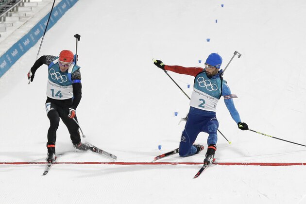 Simon Schempp, of Germany, left, and Martin Fourcade, of France, right, cross the finish line during the men's 15-kilometer mass start biathlon at the 2018 Winter Olympics in Pyeongchang, South Korea, Sunday, Feb. 18, 2018. Fourcade won the gold medal defeating Schempp in a photo finish. (AP Photo/Andrew Medichini)