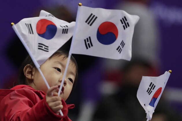 A young South Korean fan waves flags prior to the start of the men's 500 meters short track speedskating heat in the Gangneung Ice Arena at the 2018 Winter Olympics in Gangneung, South Korea, Tuesday, Feb. 20, 2018. (AP Photo/Julie Jacobson)
