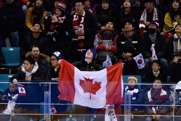 A fan holds the Canada flag during the men's preliminary round ice hockey match between Canada and South Korea during the Pyeongchang 2018 Winter Olympic Games at the Gangneung Hockey Centre in Gangneung on February 18, 2018.   / AFP PHOTO / Brendan Smialowski        (Photo credit should read BRENDAN SMIALOWSKI/AFP/Getty Images)