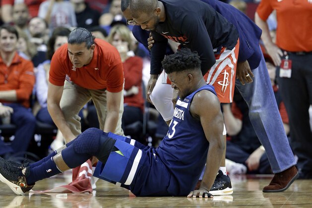 Minnesota Timberwolves guard Jimmy Butler (23) reacts to a knee injury on the court as Houston Rockets guard Chris Paul (3) and team trainers hover over him during the second half of an NBA basketball game Friday, Feb. 23, 2018, in Houston. (AP Photo/Michael Wyke)