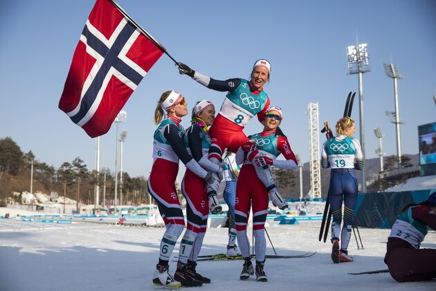 Norway's Marit Bjoergen is lifted by her compatriots as she waves the Norwegian flag after winning gold in the women's 30km cross country mass start classic at the Alpensia cross country ski centre during the Pyeongchang 2018 Winter Olympic Games on February 25, 2018 in Pyeongchang.  / AFP PHOTO / Odd ANDERSEN        (Photo credit should read ODD ANDERSEN/AFP/Getty Images)