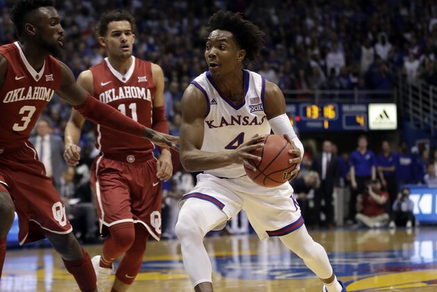 Kansas guard Devonte' Graham (4) and Oklahoma forward Khadeem Lattin (3) during the first half of an NCAA college basketball game in Lawrence, Kan., Monday, Feb. 19, 2018. (AP Photo/Orlin Wagner)
