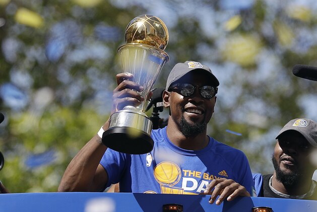 Golden State Warriors' Kevin Durant smiles as he holds the NBA Finals MVP trophy during a parade and rally after winning the NBA basketball championship Thursday, June 15, 2017, in Oakland, Calif. (AP Photo/Marcio Jose Sanchez)