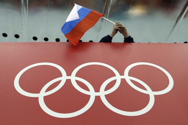 FILE - In this Feb. 18, 2014 file photo, a Russian skating fan holds the country's national flag over the Olympic rings at Adler Arena Skating Center during the 2014 Winter Olympics in Sochi, Russia. The Court of Arbitration for Sport has received 20 more appeals from Russian athletes against Olympic doping bans, taking the total to 42. The athletes' appeals will be fast-tracked. CAS said those cases will be heard together in the week beginning Jan. 22, and it expects verdicts will be issued by Jan. 31. (AP Photo/David J. Phillip, File)