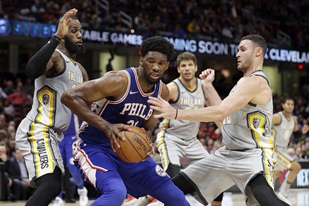 Philadelphia 76ers' Joel Embiid, center, from Cameroon, dribbles against Cleveland Cavaliers' LeBron James and Larry Nance Jr. in the second half of an NBA basketball game, Thursday, March 1, 2018, in Cleveland. (AP Photo/Tony Dejak)